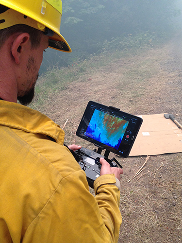 UAS specialist monitoring data on handheld device.