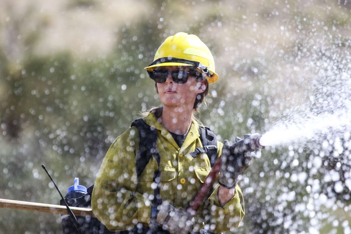 A female firefighter holding a hose.