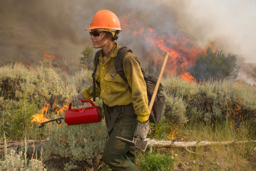 photo of firefighter walking with a drip torch