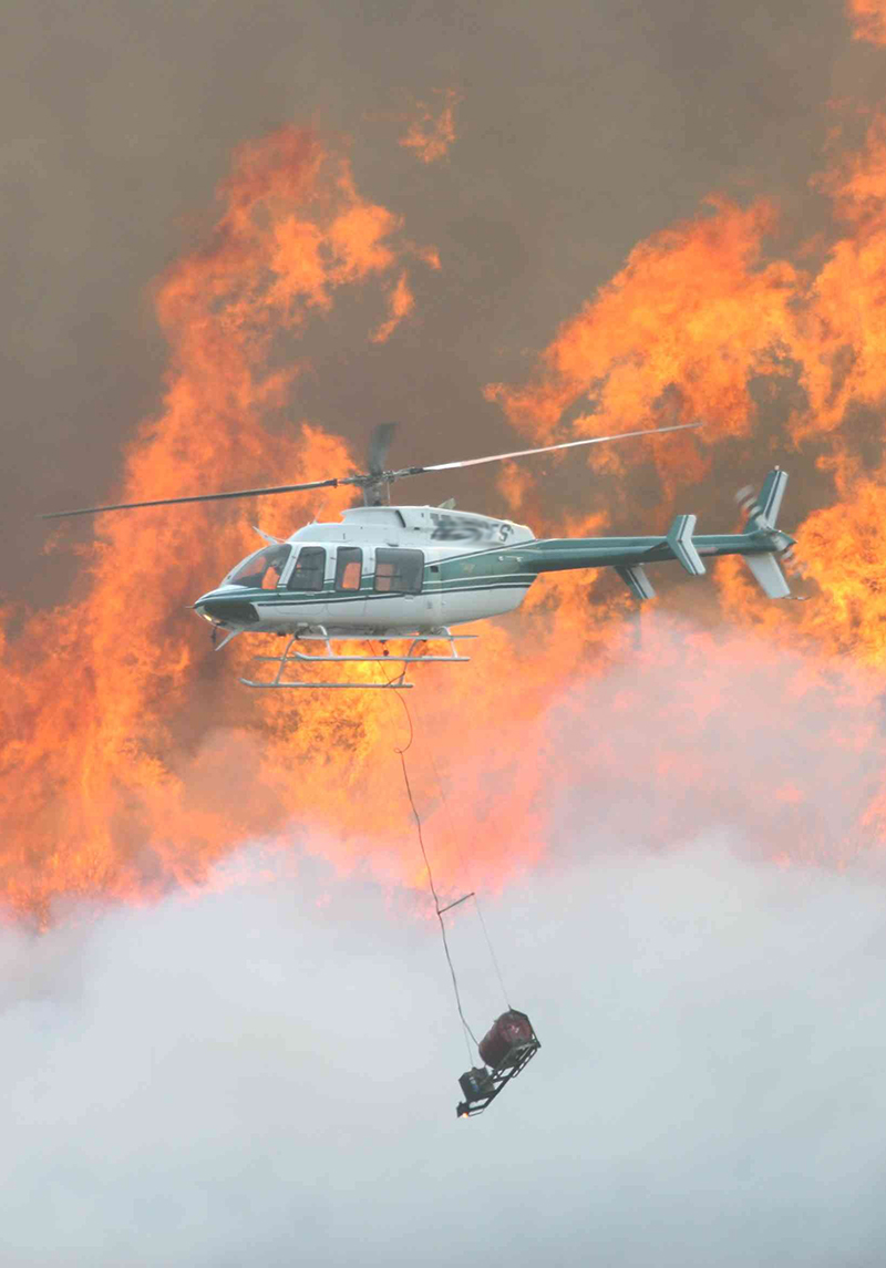 photo of helicopter with flames in the background