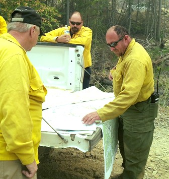 Division personnel examining a topographic map in the back of a truck tailgate.