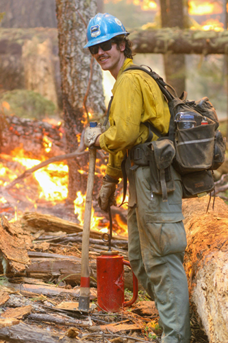 photo of wildland firefighter with drip torch in full personal protective equipment.