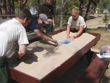 Photo of group of students working in a sandbox moving sand.