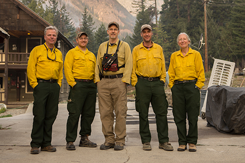 Five fire leadership personnel standing in a group smiling at camera.