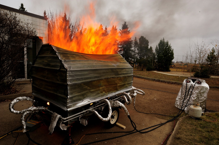 Shelter on a trailer connected to a small fuel tank.  Flames bursting from the top. 