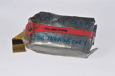 A metallic shelter in a clear bag labeled Out of Service Used For Training Only