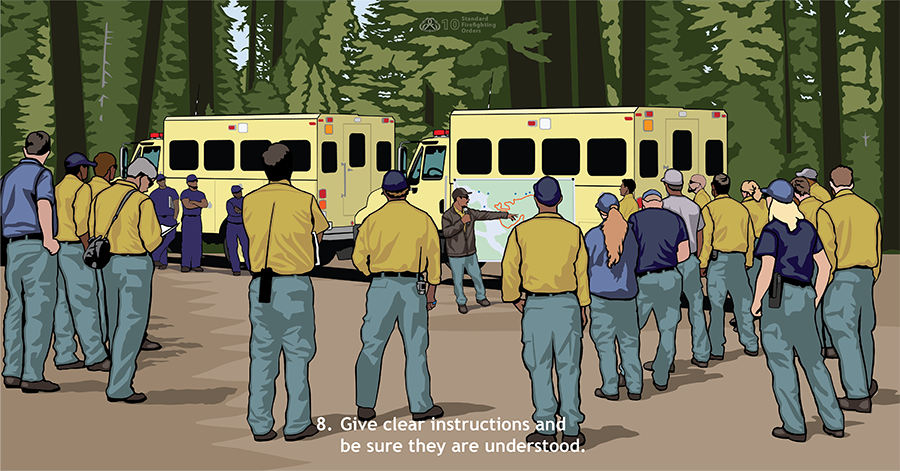Give clear instructions and be sure they are understood. About 20 firefighters stand in a semi-circle in front of two crew buggies where a map has been put up.  A supervisory firefighter points at the map and speaks to the group.