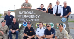 Photo of  international fire crew in front of NIFC sign.