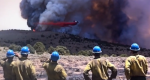 Photo of firefighters watching an airtanker drop retardant on fire.