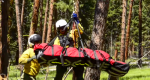 Image of firefighters loading an individual onto the end of a tether for a short-haul evac.