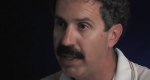 Photo of man with dark curly hair and mustache speaking.