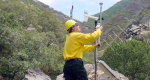 Image of a firefighter adjusting a RAWS unit in a canyon with brush and rocks.