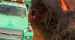 Photo of fire truck with flames burning very near by.